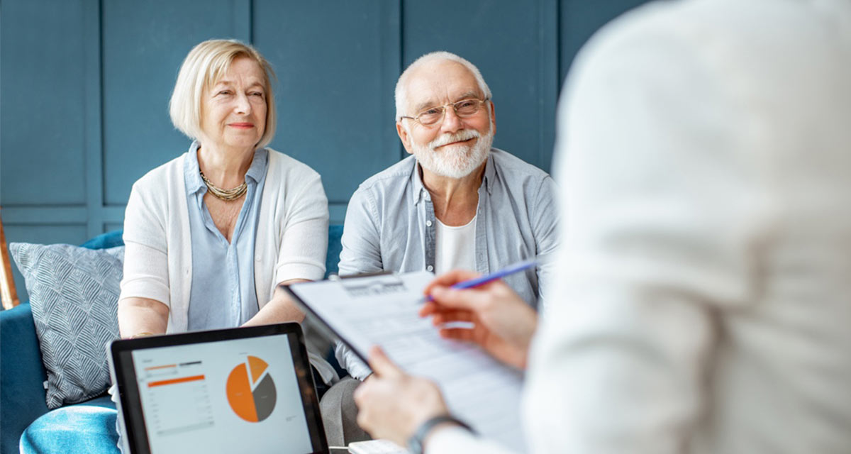 Happy Residents Older couple smiling while being evaluated by consultant with laptop