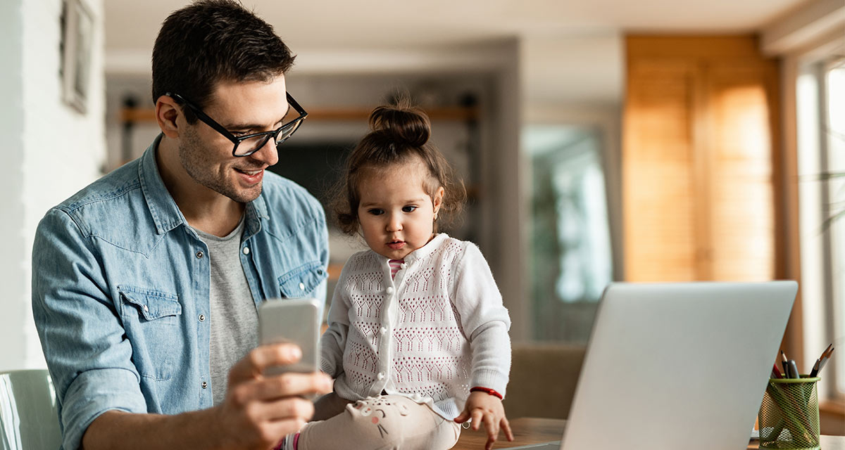 Digital Relationship Father in blue shirt showing his young daughter his cellphone and computer