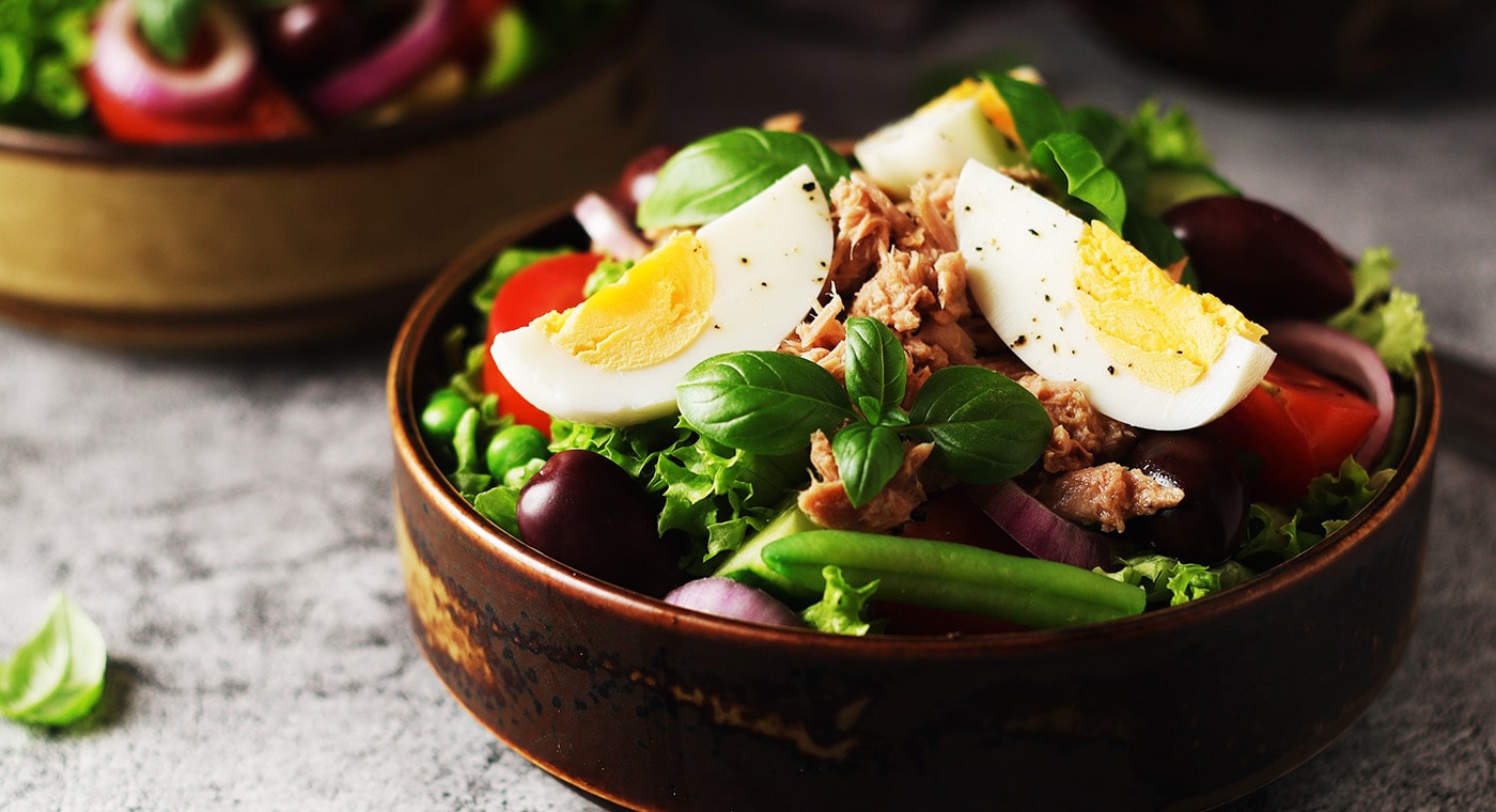 Low Cost Ingredients Salad in bowl with eggs, olives, tomatoes, lettuce