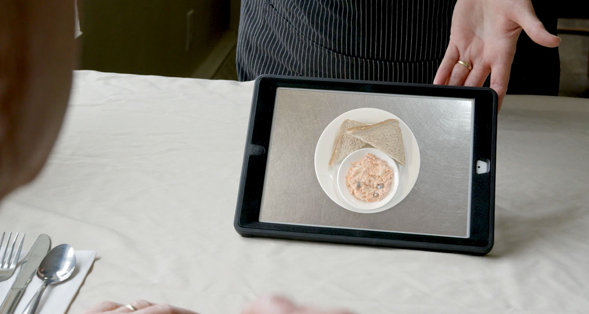 Improved Communications Using Software on Tablets Facility care worker showing longterm care resident food options on a tablet using MealSuite<sup>®</sup> Touch