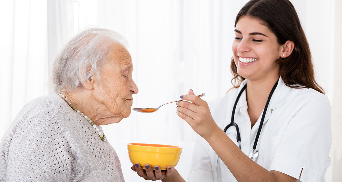 Memory Care - Motor & Swallowing Difficulties Longterm Care Worker feeding resident a bowl of soup