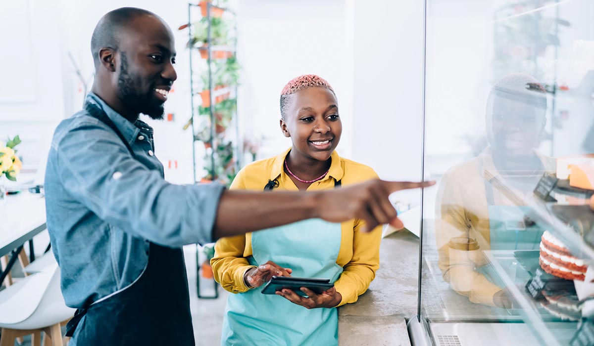 Employees African Amercian man in blue shirt and African American woman in yellow working in cafe