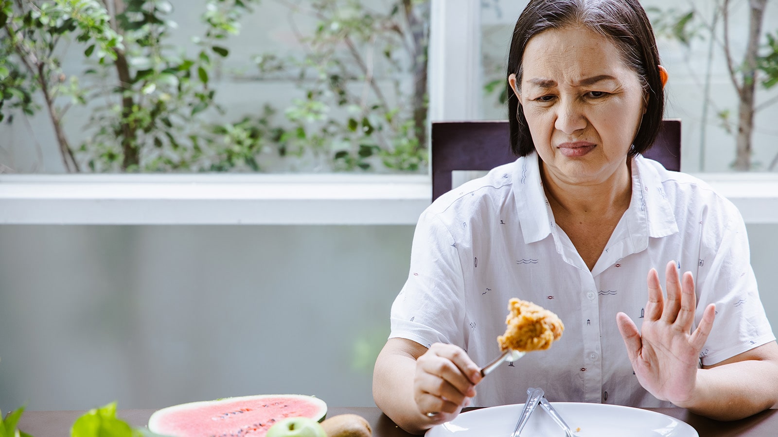 Resident Dislikes Asian woman in white shirt showing disklike of food on fork