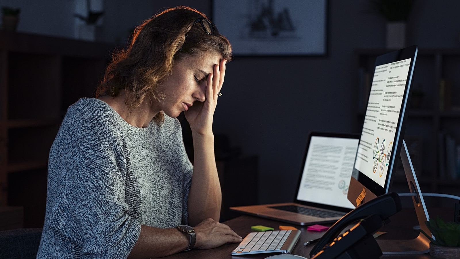Woman with hand on head at desk stressed out Woman with hand on head at desk stressed out