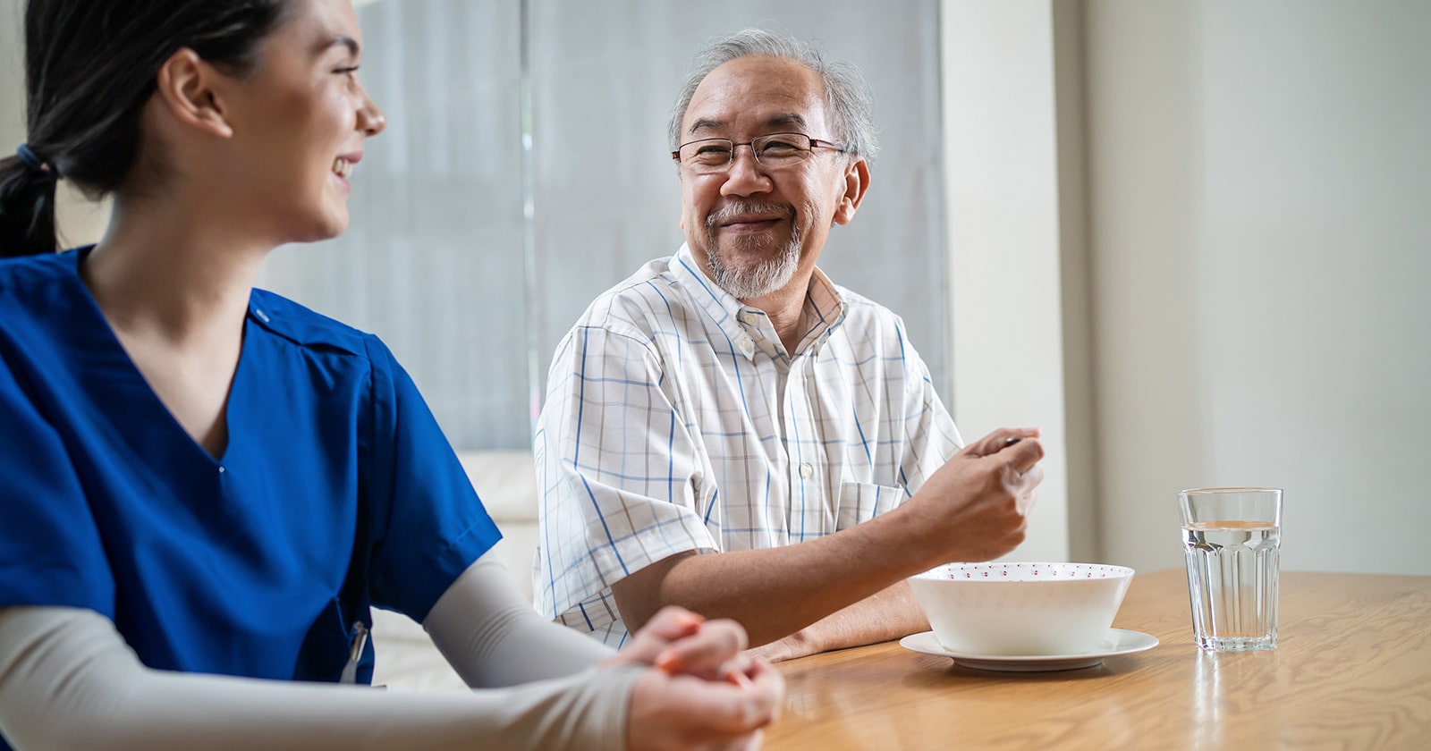 Patient Satisfaction Older asian man wearing white smiling at nurse wearing blue