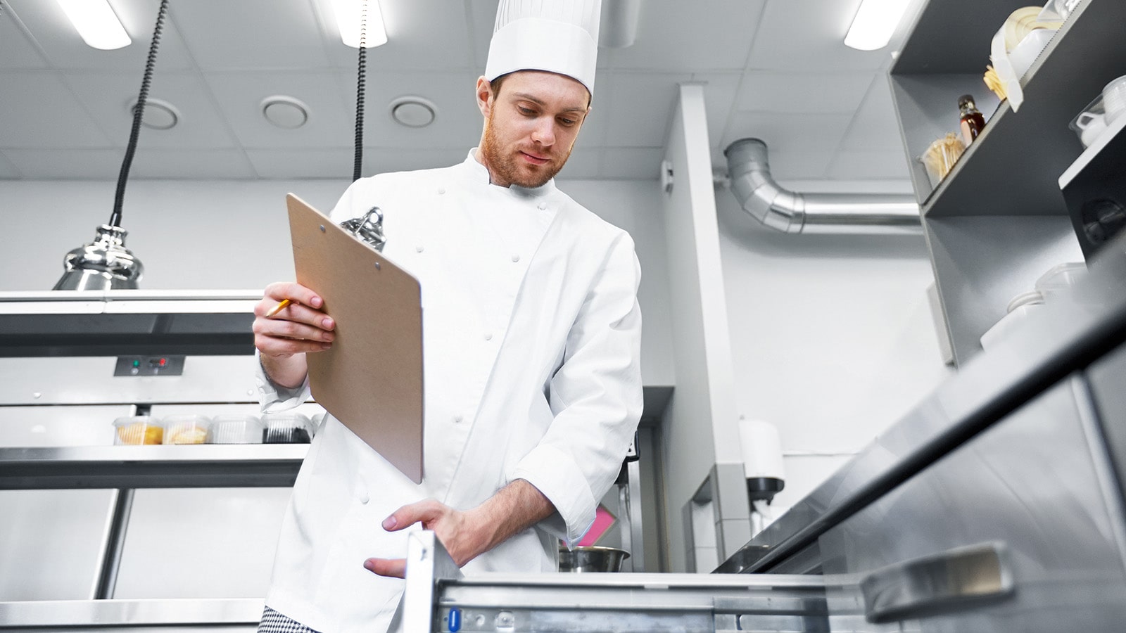 Manual temperature tracking Male chef cook with clipboard doing inventory
