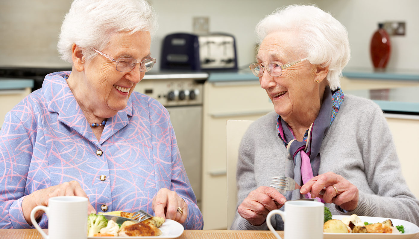 Excitement and Smiles Senior womean with white hair and glasses sharing a laugh while eating meal